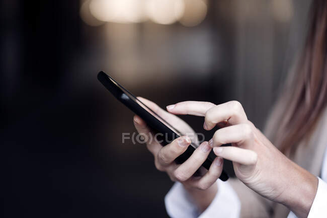 Junge Geschäftsfrau mit SMS über Smartphone — Stockfoto