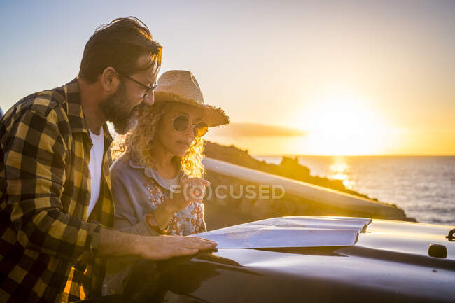 Reifes Paar liest Karte im Auto bei Sonnenuntergang — Stockfoto