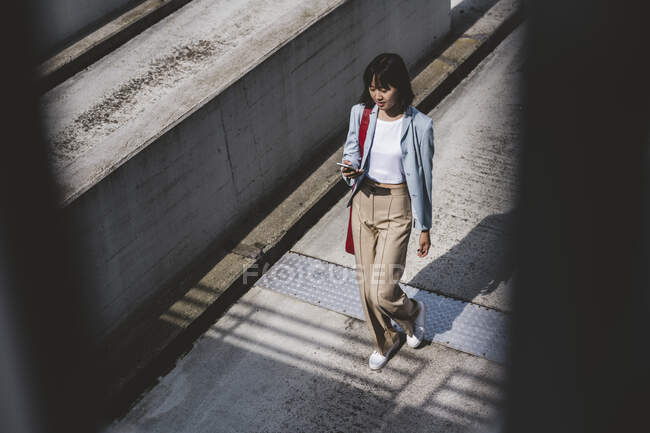 Adolescente chica usando el teléfono móvil mientras camina en la azotea - foto de stock