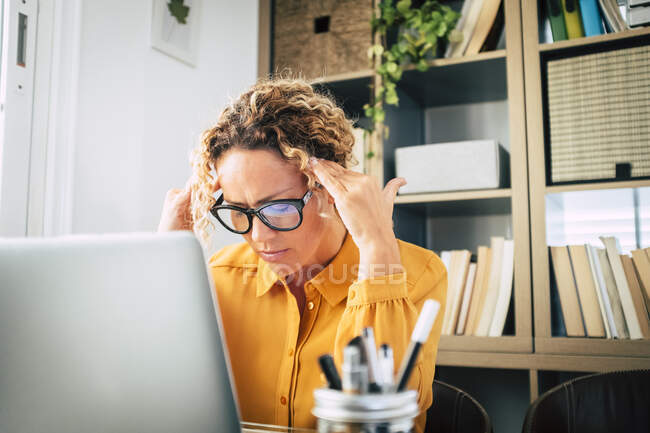 Stressato freelance femminile seduto davanti al computer portatile a casa — Foto stock