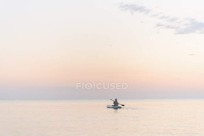 Ragazzo con remo paddleboarding in mare durante il tramonto — Foto stock
