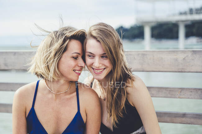 Lächelnde Mutter und Tochter im Cocktailkleid vor dem Geländer — Stockfoto
