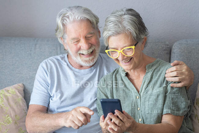 Щасливий чоловік похилого віку жестом під час відеодзвінка жінка сидить на дивані — стокове фото