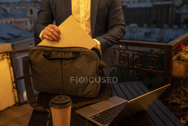 Hombre profesional poner documento en bolsa en la mesa durante la noche - foto de stock