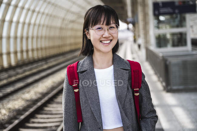 Sorrindo adolescente usando mochila na estação de trem — Fotografia de Stock
