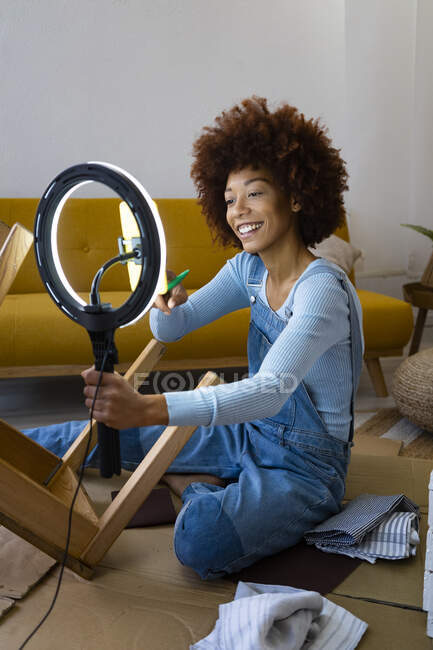 Vlogger femenina transmitiendo en vivo mientras pinta silla en casa - foto de stock