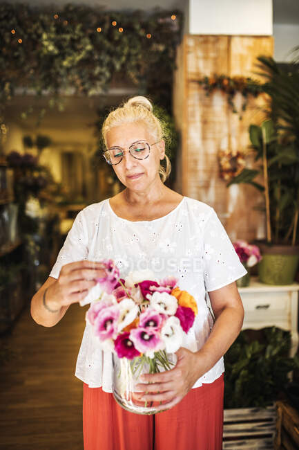 Maturo fiorista femminile organizzare fiore in vaso al negozio — Foto stock