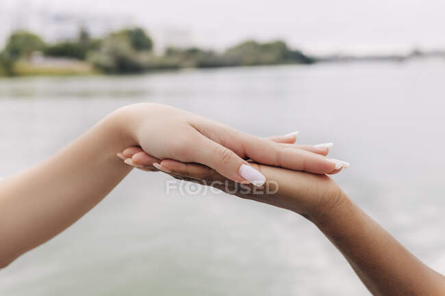 Femmes touchant les mains par le lac — Photo de stock