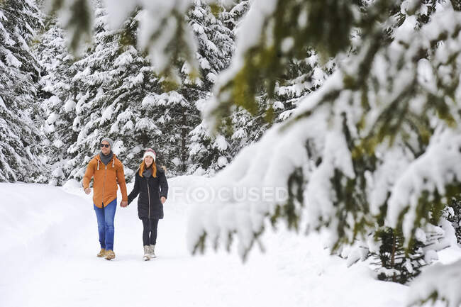Мужчина и женщина наслаждаются отдыхом во время прогулки по снегу зимой — стоковое фото