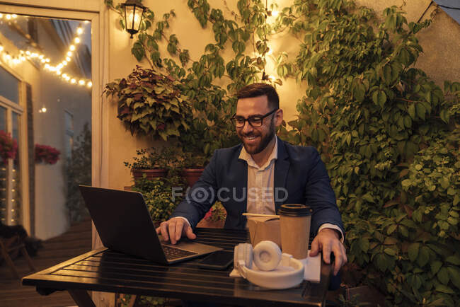 Чоловік-професіонал використовує ноутбук на офісному балконі під час заходу сонця — стокове фото