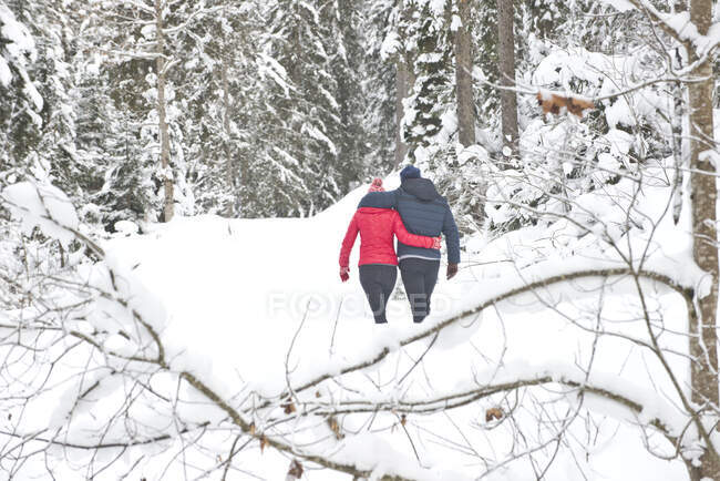 Мужчина и женщина обнимают друг друга, ходят по снегу зимой — стоковое фото
