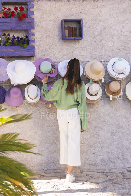 Donna che sceglie cappelli da parete — Foto stock