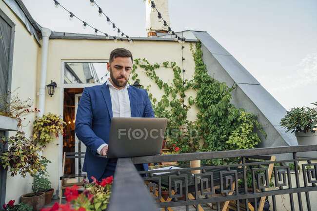 Homme d'affaires utilisant un ordinateur portable sur la rampe au balcon du bureau — Photo de stock