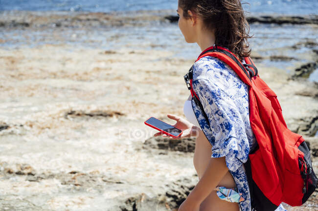 Permiso Pronunciar Casi Mujer adulta que lleva mochila con teléfono inteligente en la playa durante  el verano — aire libre, independencia - Stock Photo | #522993776