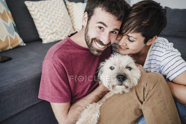 Sorrindo homem e mulher sentado com cão mestiço em casa — Fotografia de Stock