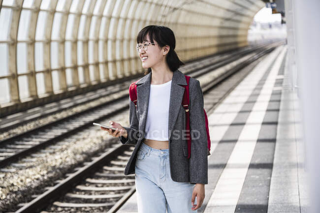Lächelnde Teenagerin mit Handy am Bahnhof — Stockfoto