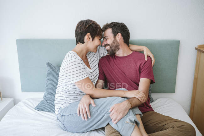 Romantic couple sitting together on bed at home — Stock Photo