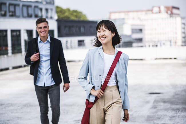 Empresária vestindo bolsa de ombro andando com colega masculino no telhado — Fotografia de Stock