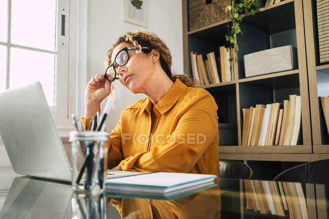 Donna d'affari con gli occhi chiusi rimuovere gli occhiali alla scrivania — Foto stock