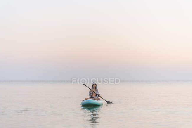 Ragazzo paddleboarding in mare durante il tramonto — Foto stock