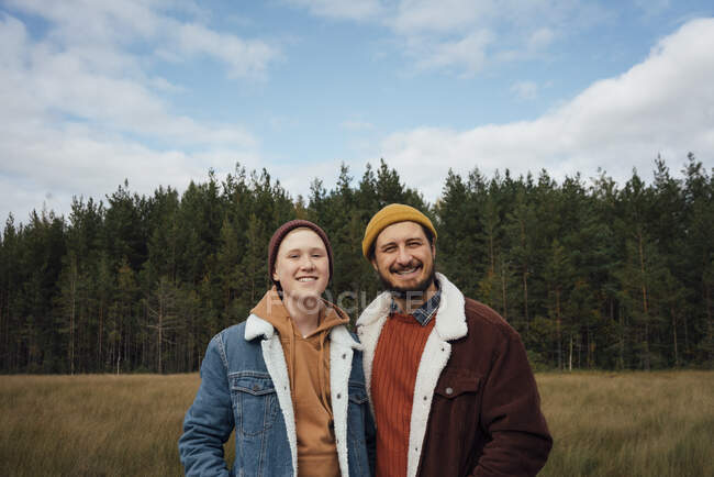 Sorridente padre e figlio in piedi insieme nella foresta — Foto stock