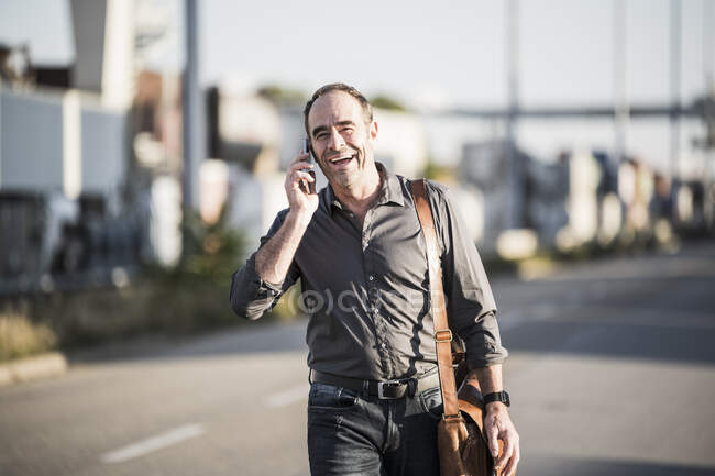 Allegro uomo d'affari che parla su smart phone mentre va al lavoro — Foto stock
