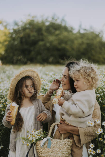 Ragazzo e ragazza che hanno cibo con madre al campo di fiori — Foto stock