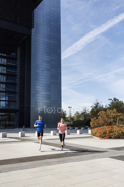 Чоловіки і жінки спортсмени практикують під час бігу в місті — стокове фото