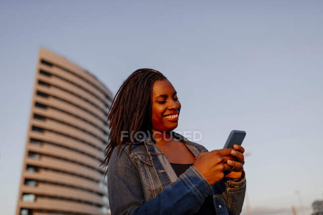 Donna sorridente che utilizza lo smartphone in città — Foto stock