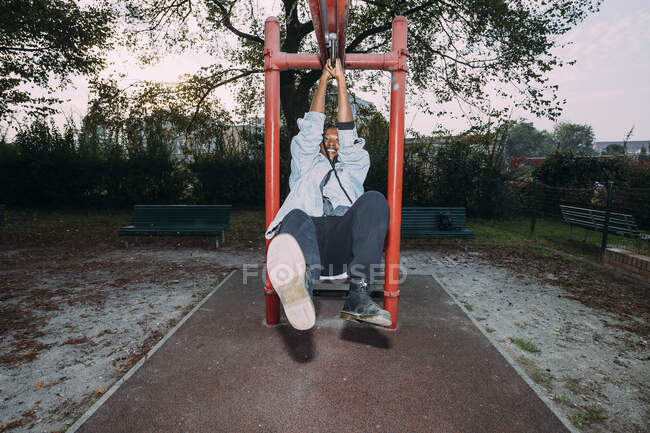 Игривая женщина висит на оборудовании в парке — стоковое фото