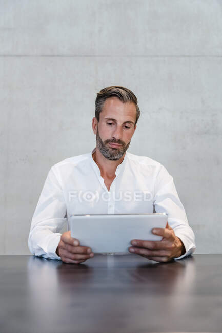 Businessman using tablet PC in front of wall — Stock Photo
