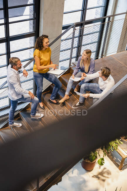 Femme d'affaires discutant avec des collègues sur les marches dans le bureau — Photo de stock