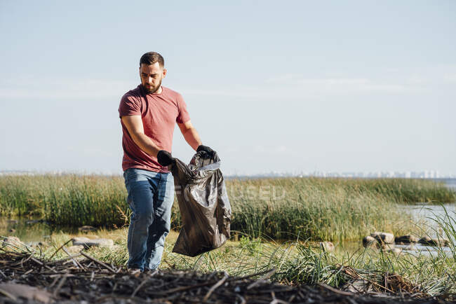 Мужчина-активист обыскивает мусор в солнечный день — стоковое фото
