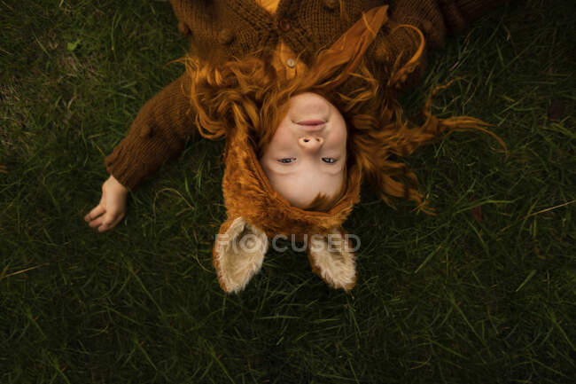 Carino rossa ragazza sdraiata su erba nel parco — Foto stock