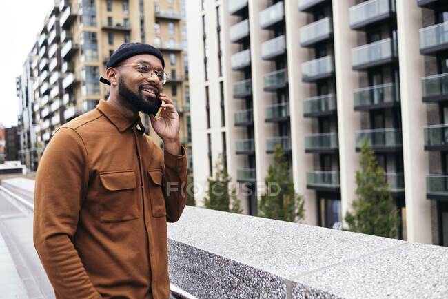 Улыбающийся мужчина разговаривает по мобильному телефону в городе — стоковое фото