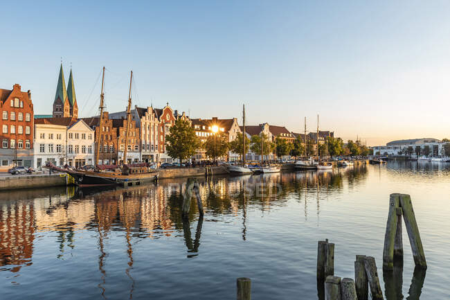 Deutschland, Schleswig-Holstein, Lübeck, Schiffe am Trave-Kanal in der Abenddämmerung mit historischen Stadthäusern im Hintergrund — Stockfoto