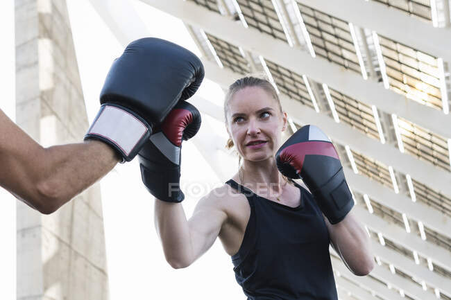 Entrenamiento de boxeadora femenina con instructor de fitness - foto de stock