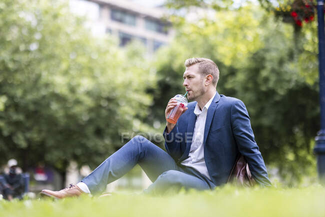Businessman having drink while sitting in park — Stock Photo