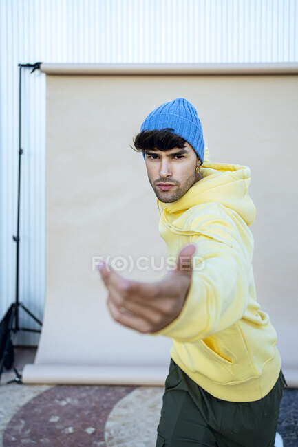Young man wearing knit hat dancing against in front of backdrop — Stock Photo