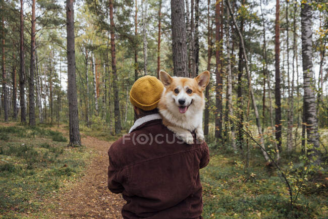 Mann trägt Hund auf Fußweg im Wald — Stockfoto