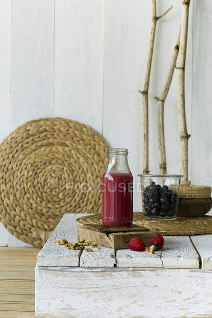 Bottle of fresh strawberry and blueberry smoothie standing on wooden surface — Stock Photo