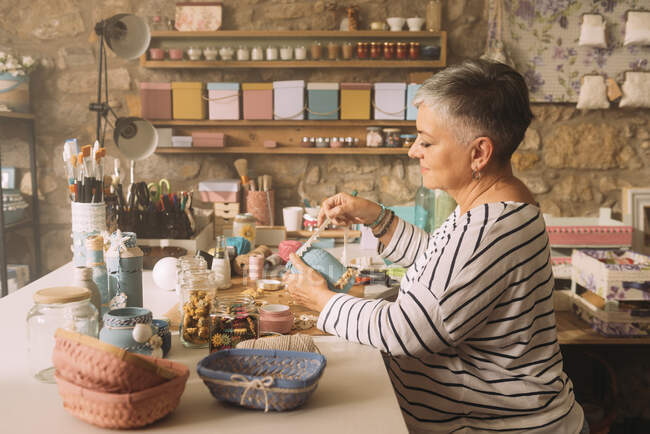 Artiste femme décorant pot sur établi — Photo de stock
