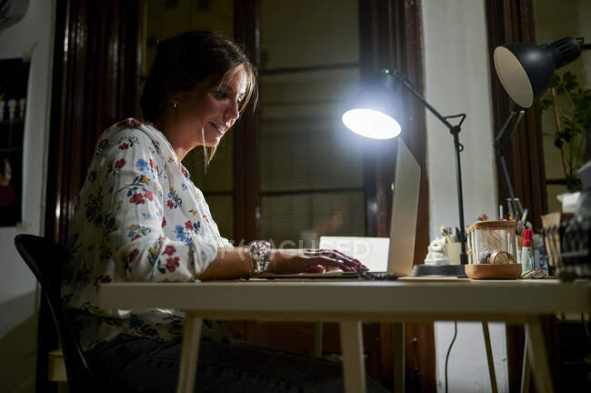 Деловая женщина работает на ноутбуке с электрической лампой в офисе в ночное время — стоковое фото