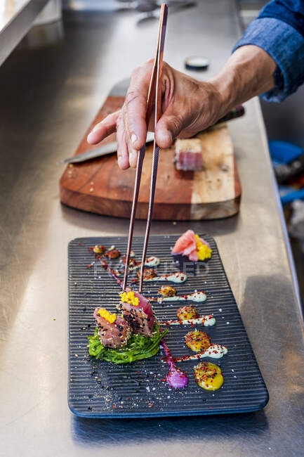 Chef masculin décorant la nourriture par pince à épiler dans la cuisine — Photo de stock
