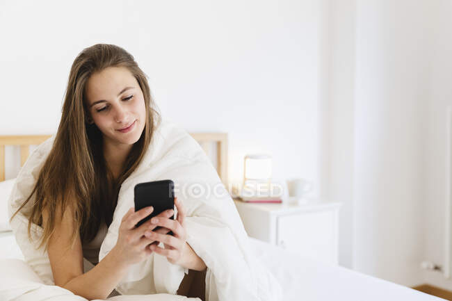 Smiling young woman with brown hair using smart n bed — Stock Photo