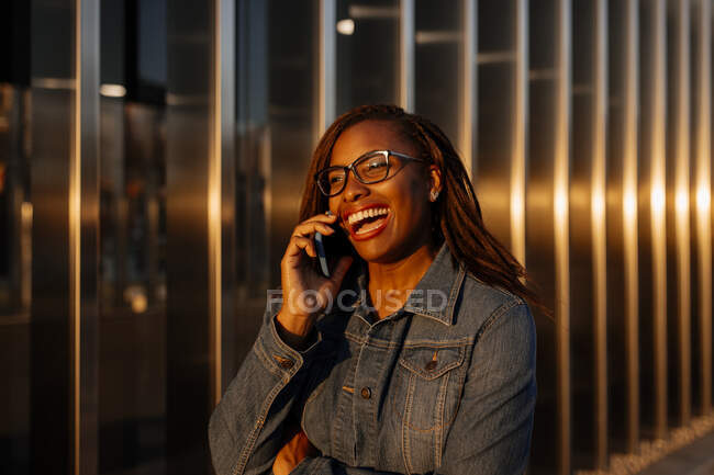 Веселая женщина в очках разговаривает по смартфону — стоковое фото