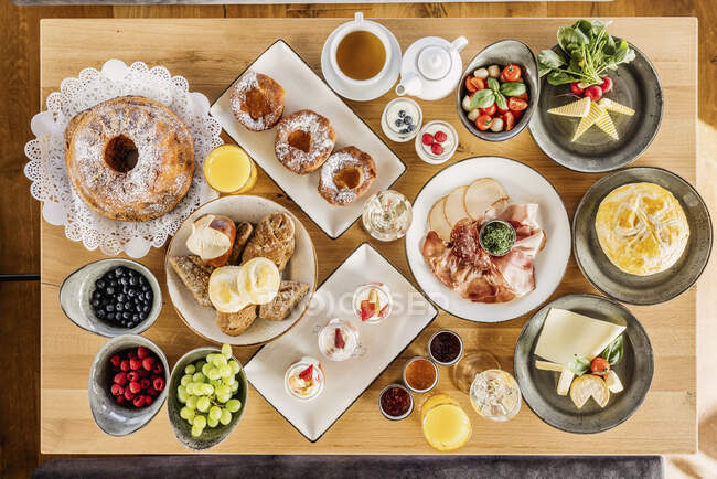 Studio shot of breakfast table filled with various desserts, fruits and vegetables — Stock Photo