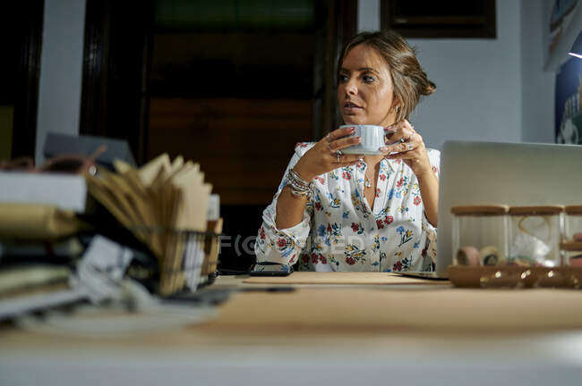 Empresaria mirando hacia otro lado mientras sostiene la taza de café en la oficina - foto de stock