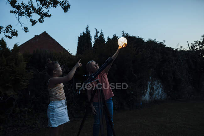 Nonna che tiene lanterna illuminata mentre in piedi con la nipote in cortile — Foto stock