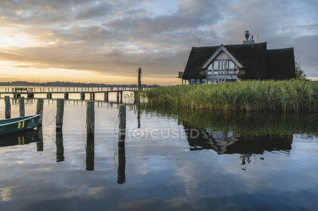 Germany, Schleswig-Holstein, Hemmelsdorf, Vogelplattform Hemmelsdorfer See and lakeshore house at sunset — Stock Photo
